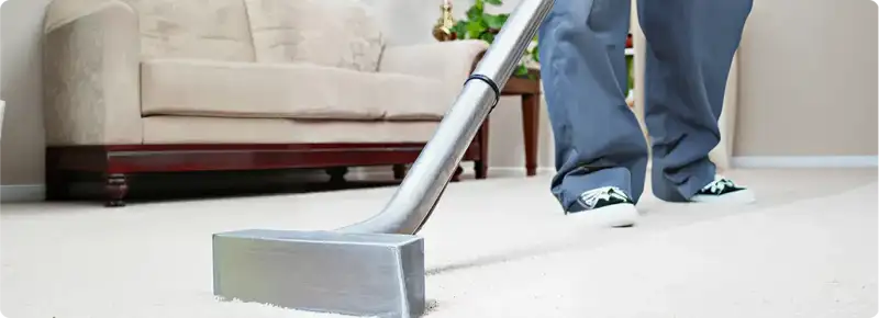 Carpet cleaning technician using a hot-water extraction wand on a light-colored carpet in a living room, Pittsburgh, PA.